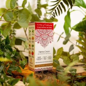 En æske Tints of Nature Henna Cream Golden Blond - 70 ml, der sidder på toppen af en plante, fremmer helbred og velvære.