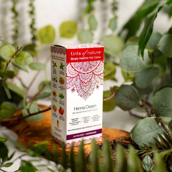 En æske Tints of Nature Henna Cream Burgundy - 70 ml siddende oven på en plante, fremmer wellness.